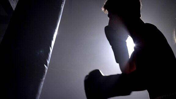 年轻拳击手戴着手套拳击在砖房里训练