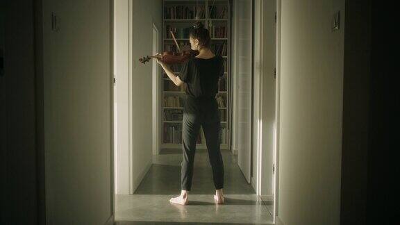 漂亮的年轻女音乐家在走廊里拉小提琴