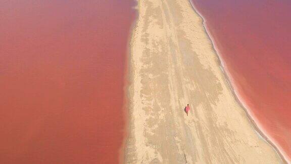 空中女孩走在沙滩上看令人惊叹的充满活力的粉红色萨利纳斯