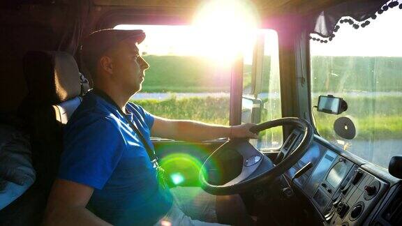 日落时分卡车司机在乡间行驶的侧面图戴着帽子的男人控制着他的卡车享受着旅程美丽的风景与明亮的阳光在背景慢镜头
