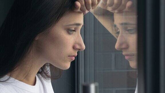 年轻女子悲伤地盯着窗外