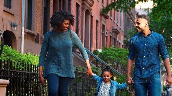 一对年轻的黑人夫妇在街上摇摆着他们的女儿
