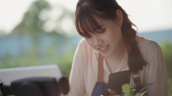 年轻的亚洲女性用平板电脑追踪自家花园里的仙人掌生长情况