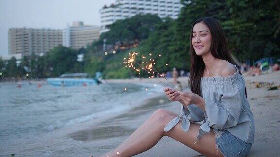 亚洲少女玩烟花美丽的光闪耀在海边在海滩夏天年轻女性节日快乐周年庆典年轻女性是旅游博主