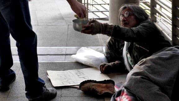 一个无家可归的老人穿着脏衣服躺在街上寻求帮助