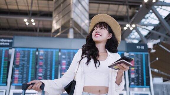 兴高采烈的亚洲年轻女子拿着护照和行李站在机场