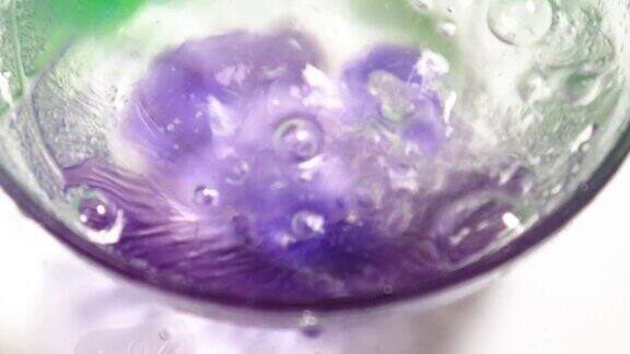 水倒进一个开着紫色花朵的玻璃碗里
