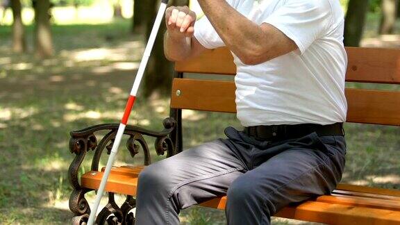 年长的盲人寻找他的手杖从长凳上站起来去散步