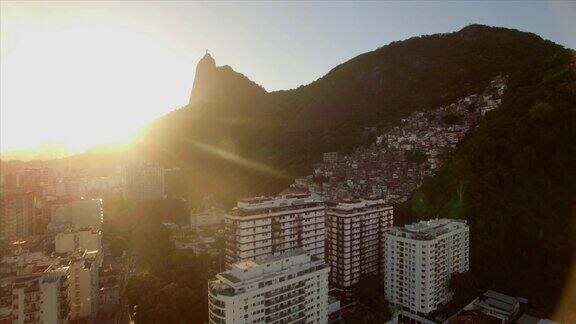 里约热内卢航拍:在前景为山区贫民窟的建筑物上方向救世主基督雕像移动