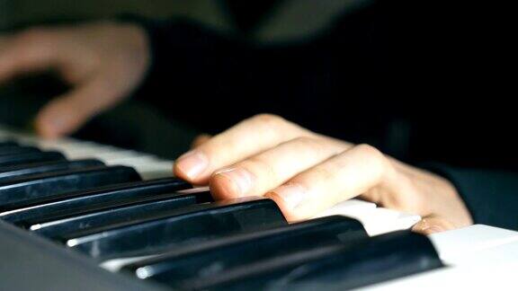 钢琴家的手指在钢琴键上弹奏在录音室合成器演奏的男音乐家之手男人的手臂演奏音乐独奏慢镜头