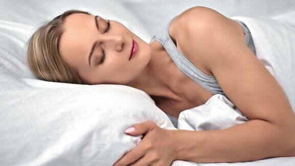 特写金发女人放松地睡在舒适的白色棉床上享受放松的压力