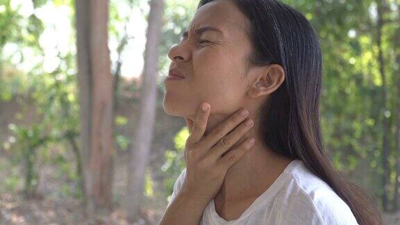 年轻的亚洲妇女触摸疼痛的脖子喉咙痛的流感感冒和感染