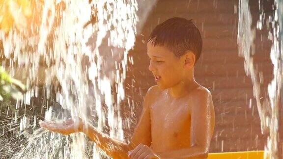 炎炎夏日男孩在水上公园的瀑布下凉爽凉爽