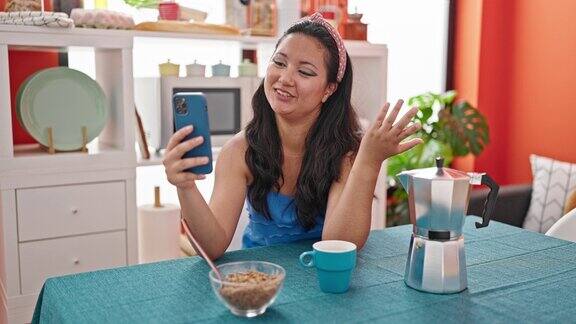 年轻的中国女子在餐厅用早餐做视频通话