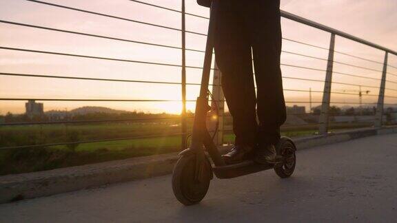 低角度:一个阳光明媚的春天早晨商人骑着电动滑板车去上班
