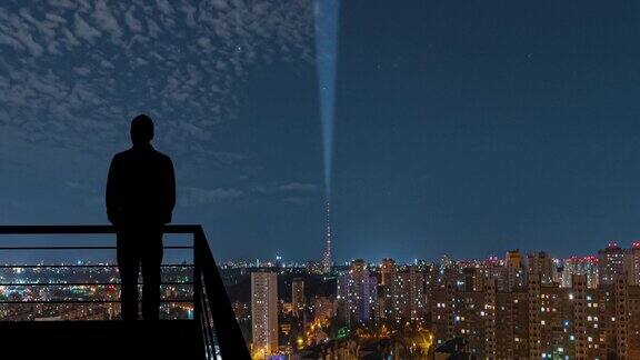 这个男人站在阳台上以城市的夜景为背景hyperlapse