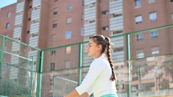 年轻女子在建筑物的背景上打网球