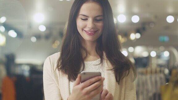 一个快乐的年轻褐发女性正在一家百货商店里使用智能手机