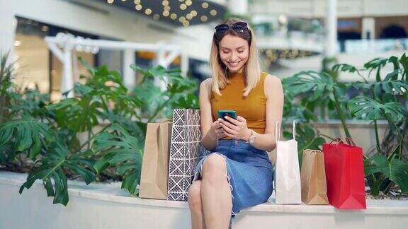 年轻的女性消费者在商场浏览聊天和使用智能手机