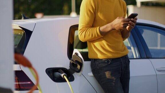 一个年轻人在给他的电动汽车充电