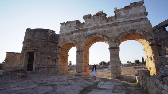帕穆克卡莱希拉波利斯古遗址的Frontinus门附近一名女游客举着相机挥舞着手臂