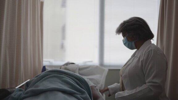 医生戴着防护口罩在病房里和病人交谈