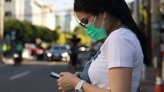亚洲年轻女子戴着面具在街上等出租车