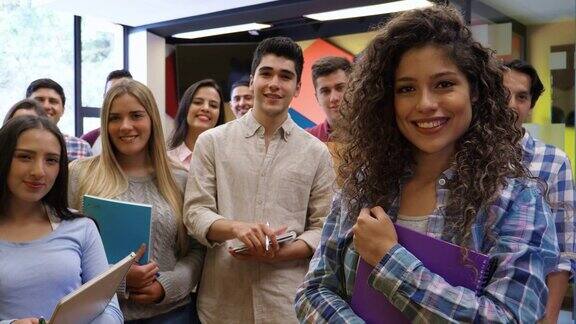 一群年轻的大学生拿着他们的笔记本看着镜头微笑