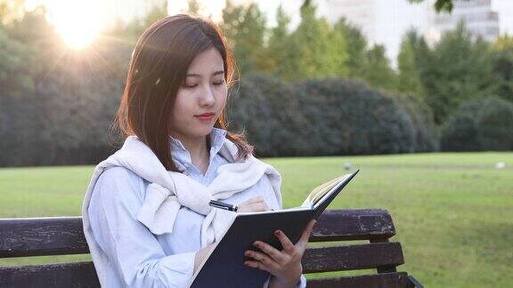 美丽的女孩在公园看书