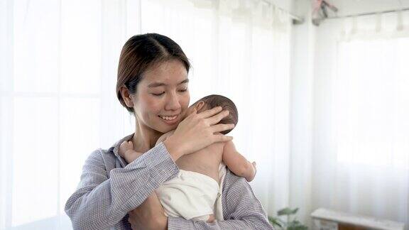 4k50fps一个2个月大的亚洲新生儿躺在妈妈的肩膀上睡觉妈妈抱着她哄她入睡爱和温暖在卧室…