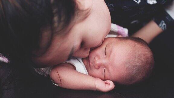 年轻的母亲亲吻她的新生儿