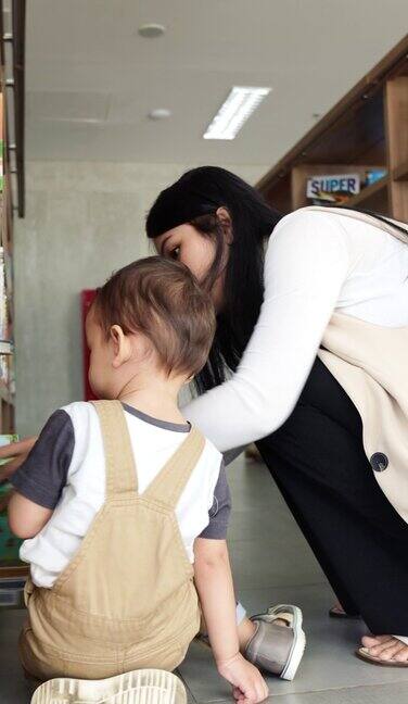 年轻的妈妈在图书馆给可爱的小儿子读书