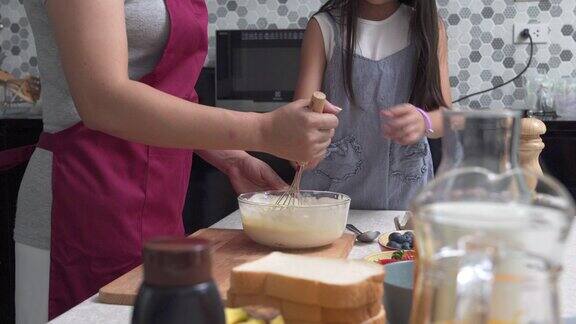 妈妈和可爱的小女儿在厨房里一起准备做煎饼
