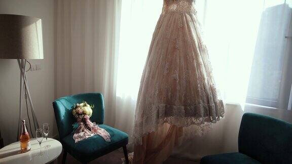 婚礼的一切都准备好了豪华现代婚纱挂在窗口婚礼花束在沙发椅子