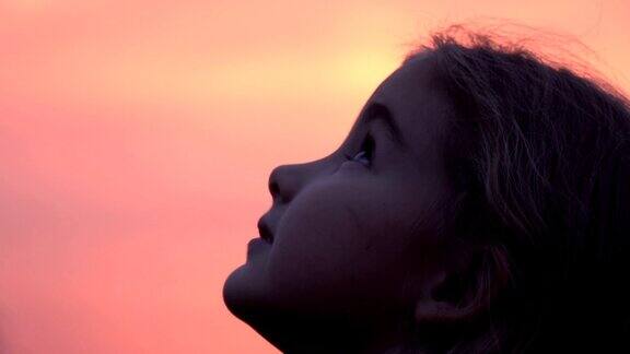 孩子在大自然中仰望天空小女孩祈祷着仰望着紫色的天空带着希望特写