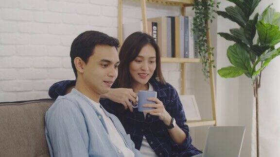 年轻的亚洲情侣情侣一起工作笔记本电脑和喝咖啡在一个房间在家里的背景自由职业者夫妇使用在线技术工作4k慢动作