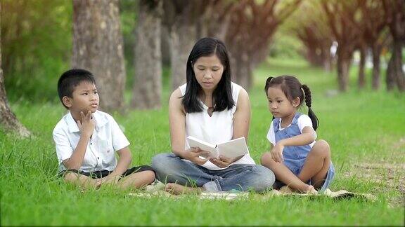 慢镜头幸福的家庭母亲女儿和儿子一起在花园里读书活动