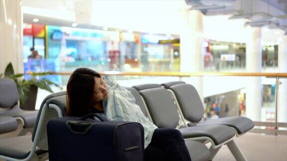 迷人的亚洲女旅行者和她的行李在机场候机大厅睡觉的4k视频场景运输和乘客旅行