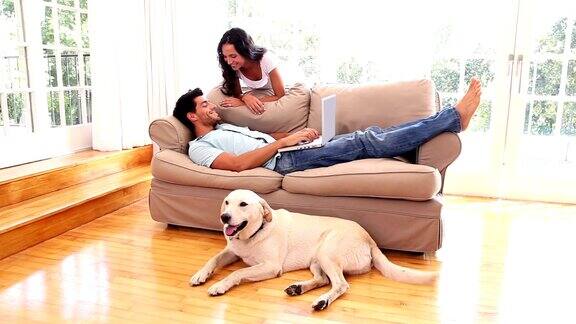 一对迷人的夫妇和宠物拉布拉多犬在客厅里放松