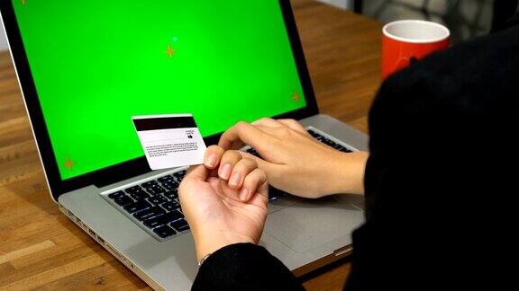 女商人用绿屏笔记本电脑输入信用卡信息
