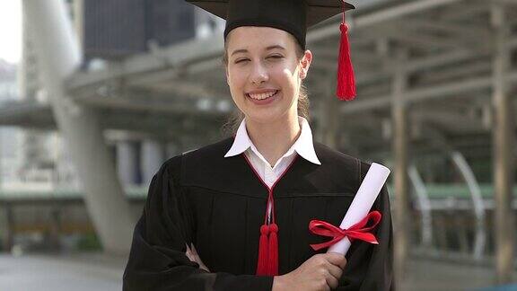 成功的毕业生们穿着学术服装拿着文凭对着镜头微笑