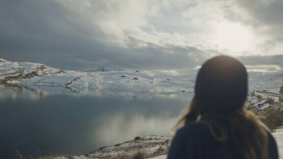 在挪威的湖边徒步旅行的女人:冬天的颜色和心情