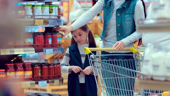 一个小女孩和她的家人在超市挑选罐头的肖像
