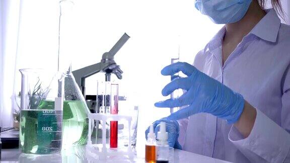 一名手持试管和注射器的女化学家正在现代实验室里用试剂做实验