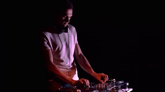 年轻的DJ在夜总会的聚会上混音唱片俱乐部唱片骑师在舞台上表演