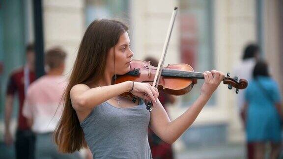 年轻的黑发女子在步行街拉小提琴
