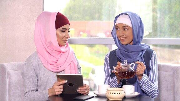 穆斯林妇女在咖啡馆聊天和使用手机