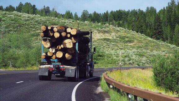 在一个阳光明媚的日子里一辆满载原木的卡车在怀俄明州山区的高速公路上缓慢行驶