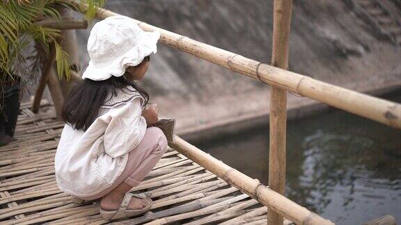 小女孩喜欢在小溪里喂鱼