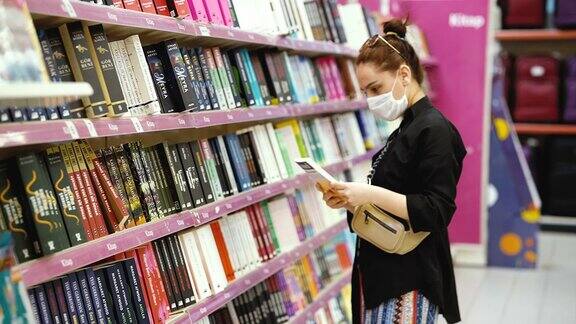 年轻女子在书店的图书区购物戴着防护医用口罩